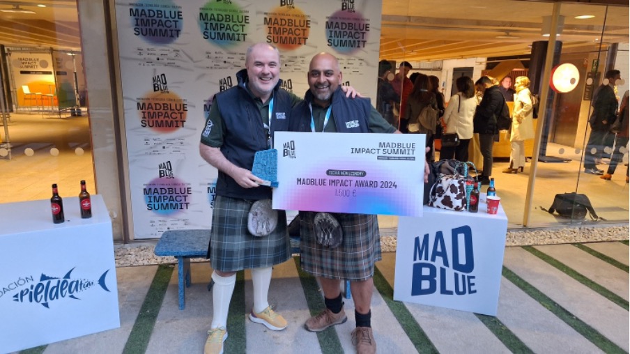 Two men in kilts holding up award in shopping centre